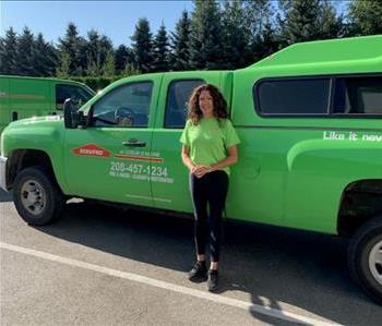Female employee standing next to a green SERVPRO vehicle 