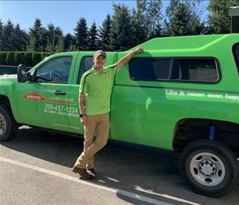 male employee standing in front of green truck