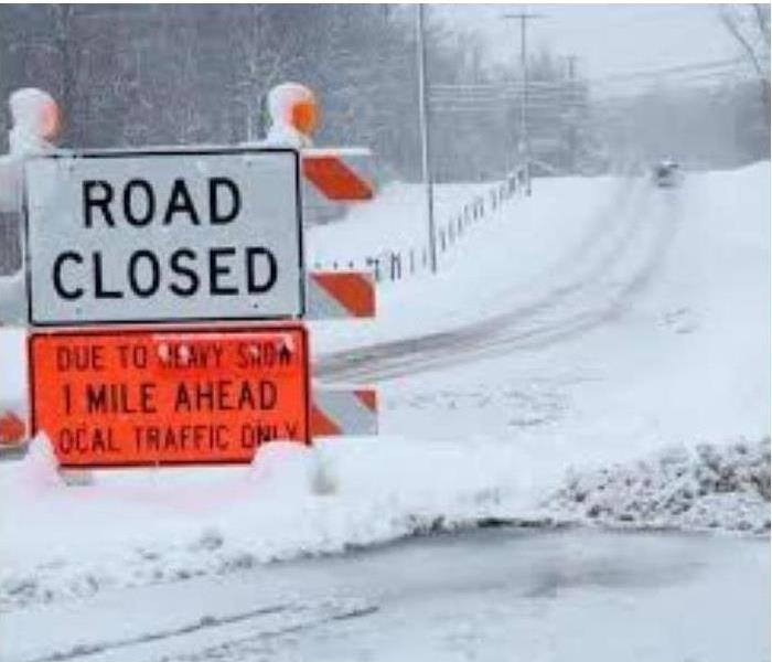 Road Closed snow storm sign in road 