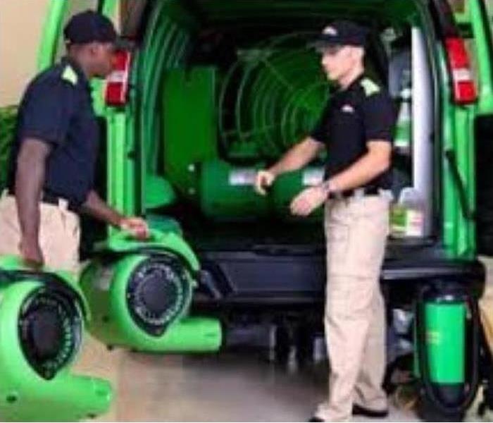 Two SERVPRO employees loading equipment into a SERVPRO green van