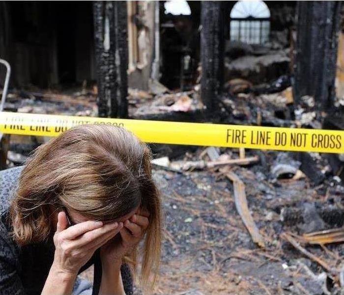 Woman on phone in front of burnt down building