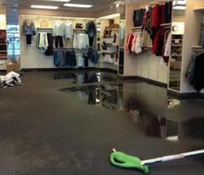 Inside of a commercial retail store with water on the floor.