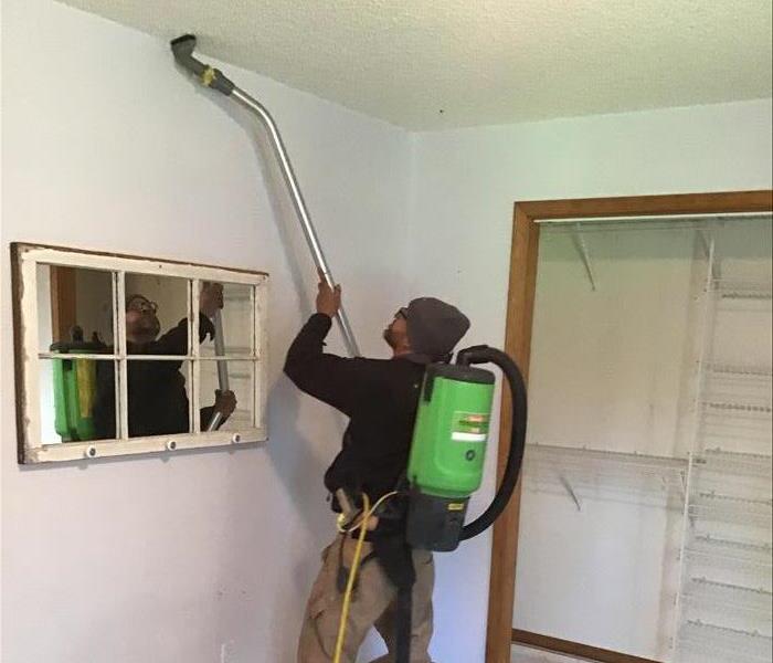 A SERVPRO employee cleaning the wall of a home